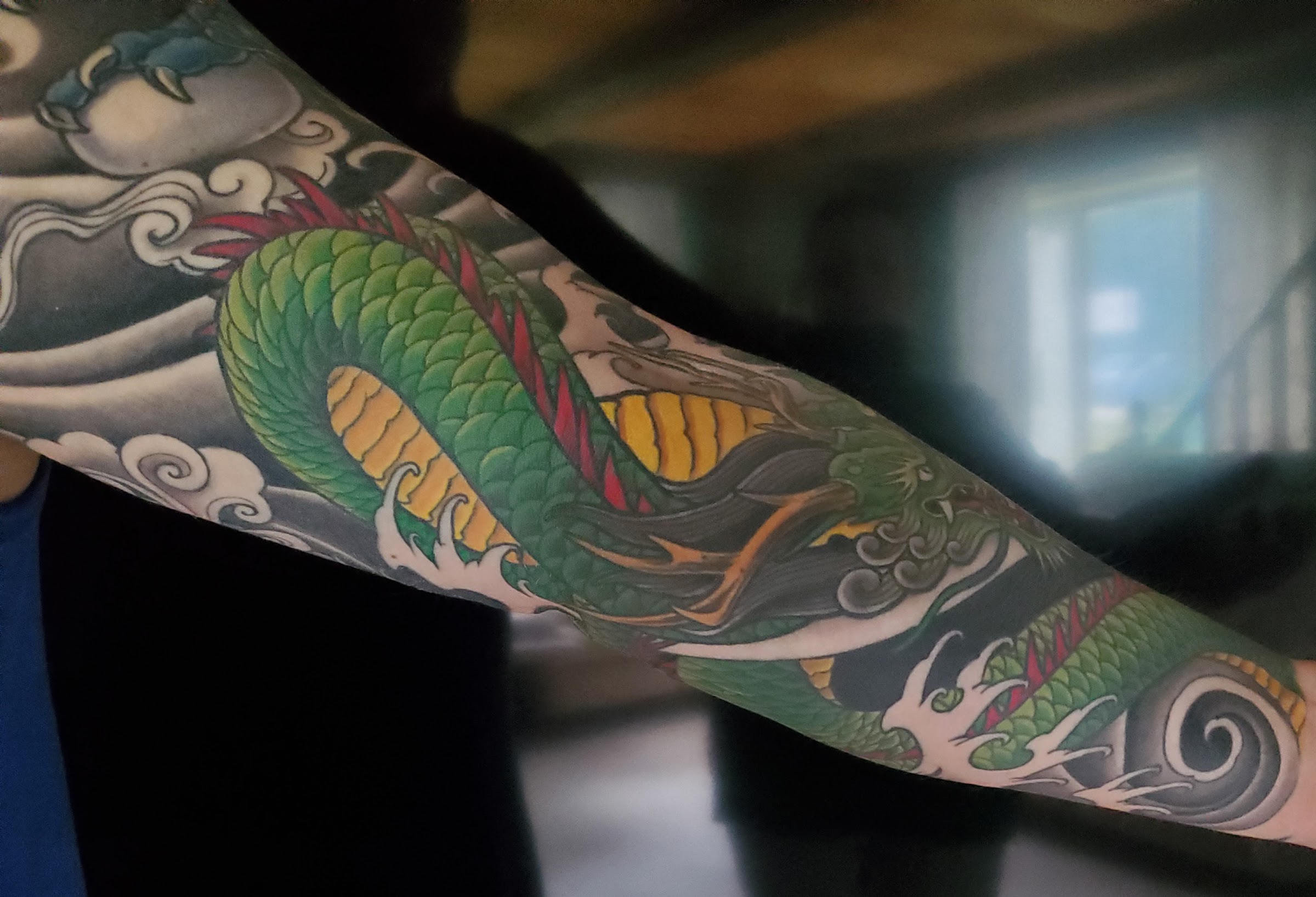 Green Japanese dragon color sleeve tattoo with waves and clouds